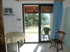 Cette chambre dispose d'une porte coulissante en verre avec une chaise. dans l'établissement Agriturismo Vaddidulimu, à Luogosanto