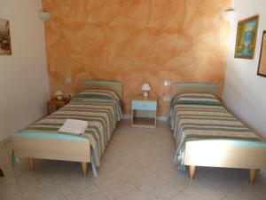 Habitación con 2 camas individuales y suelo de baldosa. en Agriturismo Vaddidulimu en Luogosanto