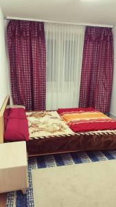 Schlafzimmer mit einem Bett mit roter Bettwäsche und Vorhängen in der Unterkunft Messezimmer Hannover Mittelfeld - room agency in Hannover
