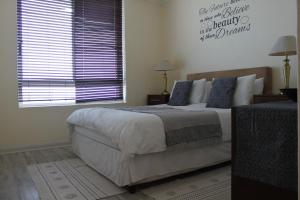 a bedroom with a large bed and a window at Portico 203 in Bloubergstrand