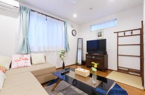 uma sala de estar com um sofá e uma televisão em Haneda Luxury House em Tóquio