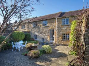 an old stone house with tables and chairs in the yard at Box Cottage in Broadway