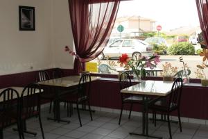 a dining room with tables and chairs and a window at Hotel de l'Avenue in Bonson
