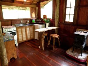 a kitchen with wooden floors and a table with flowers on it at Chalé Candeia no Matutu in Aiuruoca
