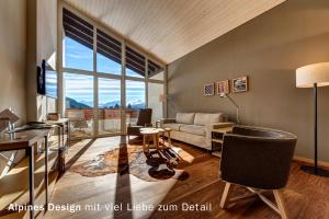 a living room with a large window and a couch at Valbella Resort in Lenzerheide
