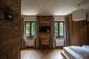 a bedroom with wooden walls and two windows and a bed at Orobie Alps Resort in Roncobello