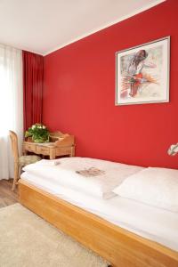 a bedroom with a large bed with a red wall at Stadthotel Langenfeld in Langenfeld