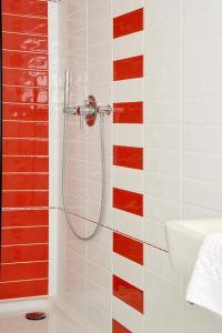 a shower in a bathroom with red and white tiles at Stadthotel Langenfeld in Langenfeld