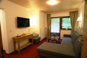 sala de estar con sofá y TV en Alpenchalet Bianca, en Ramsau