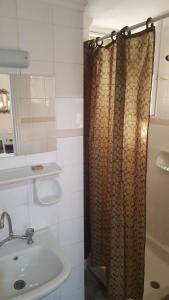 y baño con cortina de ducha y lavamanos. en Palataki Studios, en Loutrópolis Thermís