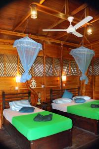 two beds in a room with wooden walls at The Green View Yala in Tissamaharama