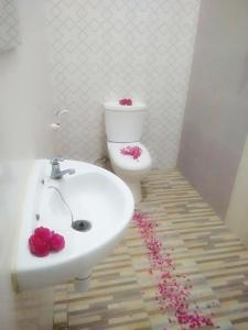 ein Badezimmer mit einem Waschbecken und einem WC mit rosa Blumen in der Unterkunft Clover Homestay in Probolinggo