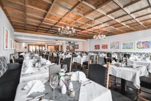 een restaurant met witte tafels en stoelen en kroonluchters bij Seefelds Bed & Breakfast in Seefeld in Tirol