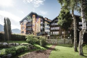 een appartementencomplex met een stenen muur en bomen bij Seefelds Bed & Breakfast in Seefeld in Tirol