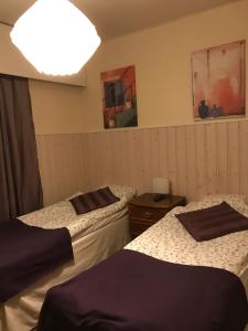a room with two beds and a light on the wall at E-City B&B in Tornio