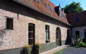 een gebouw van rode baksteen met een deur en ramen bij B&B - La Cense du Pont in Bachy