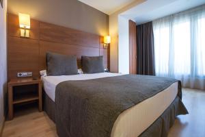 um quarto de hotel com uma cama grande e uma janela em Hotel Via Augusta em Barcelona