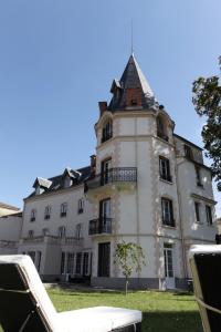 un grand bâtiment blanc avec une tour d'horloge dans l'établissement Château Les 4 Saisons, à Saint-Cirgues-sur-Couze