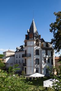 un grand bâtiment blanc avec une tour en haut dans l'établissement Château Les 4 Saisons, à Saint-Cirgues-sur-Couze