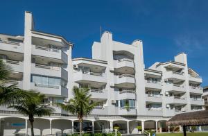 un gran edificio blanco con palmeras delante en Flat Summer, en Florianópolis