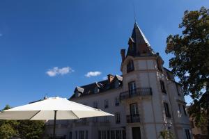 un bâtiment avec une tour d'horloge et un parapluie dans l'établissement Château Les 4 Saisons, à Saint-Cirgues-sur-Couze