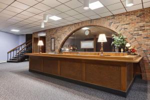 a reception desk in a lobby with a brick wall at Travelodge by Wyndham Motel of St Cloud in Saint Cloud