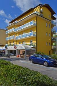 a blue car parked in front of a yellow building at Hotel Villa Olga in Caorle