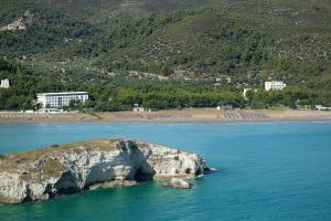 a rock in the water next to a beach at Hotel Portonuovo in Vieste