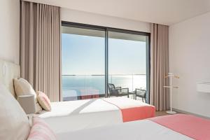 a hotel room with two beds and a large window at Searenity Vacation Home I by An Island Apart in Arco da Calheta +24 photos