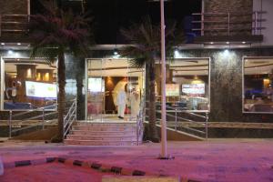 a couple walking into a store at night at Dorar Darea Hotel Apartments - Al Nafl in Riyadh