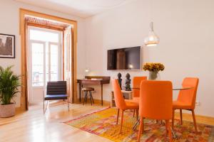 una sala da pranzo con tavolo e sedie arancioni di Charming Flat with Balconies Central Chiado District 2 Bedrooms & AC 19th Century Building a Lisbona