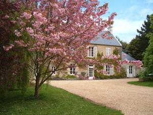 uma árvore em frente a uma casa com flores cor-de-rosa em Ferme de Savigny em La Cambe