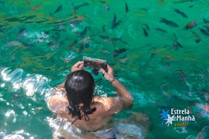 a woman taking a picture of fish in the water at Pousada Maravilha de Paraty in Paraty