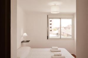 ein weißes Schlafzimmer mit einem Bett und einem Fenster in der Unterkunft Apartamento Obispo Trejo IV by Lofty in Cordoba