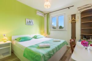 - une chambre verte avec un lit et un bureau dans l'établissement Pansion Lovac, à Cavtat