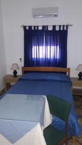 a bedroom with a blue bed and a green chair at Edificio Sagasti in Piriápolis