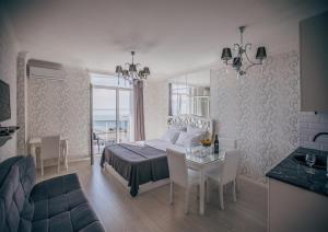 バトゥミにあるTina's Apartments with Panoramic Sea viewのベッドとテーブルと椅子のある寝室