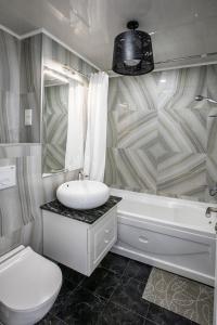 uma casa de banho com um lavatório, um WC e uma banheira em Tina's Apartments with Panoramic Sea view em Batumi