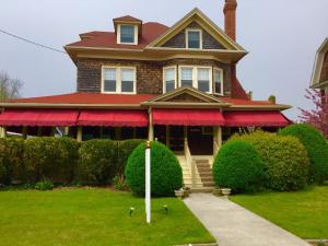 a house with a red awning and birds on the grass at Luther Ogden Inn in Cape May