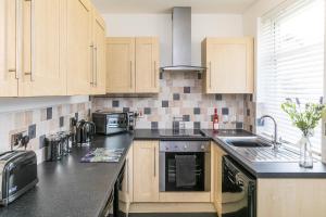 une cuisine avec des placards en bois et un comptoir noir dans l'établissement Belmont Apartments, à Billingham