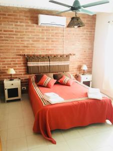 1 dormitorio con cama roja y pared de ladrillo en Residencial del Golf en Alta Gracia