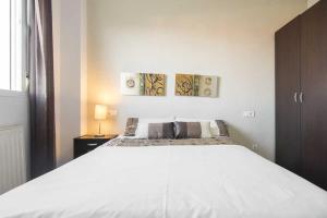 a white bed in a bedroom with two paintings on the wall at Apartamento Alcalá Real in Granada