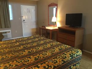 a bedroom with a bed and a desk with a television at Deerfield Inn New Johnsonville in New Johnsonville