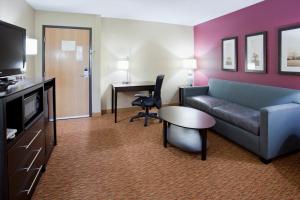 Habitación de hotel con sofá, mesa y escritorio. en AmericInn by Wyndham Osceola, en Osceola
