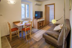 a living room with a couch and a table and a desk at Apartments Calma in Cres