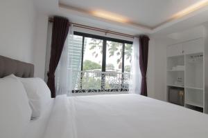 a bedroom with a white bed and a large window at Gusto House in Chiang Mai