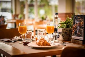 una mesa con un plato de comida y vasos de zumo de naranja en Campanile Hotel & Restaurant Vlaardingen en Vlaardingen