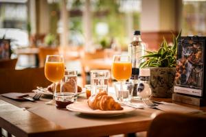 une table avec une assiette de nourriture et des verres de jus d'orange dans l'établissement Campanile Hotel & Restaurant Vlaardingen, à Flardingue