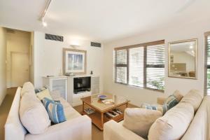 ein Wohnzimmer mit 2 weißen Sofas und einem TV in der Unterkunft Alderly Apartment 10, Little Cove in Noosa Heads