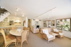 ein Wohnzimmer mit einem Tisch und Stühlen sowie eine Küche in der Unterkunft Alderly Apartment 10, Little Cove in Noosa Heads